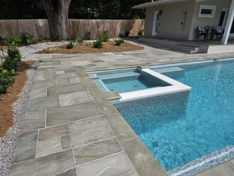 Backyard pool with spa, stone patio, and landscaping in Alachua