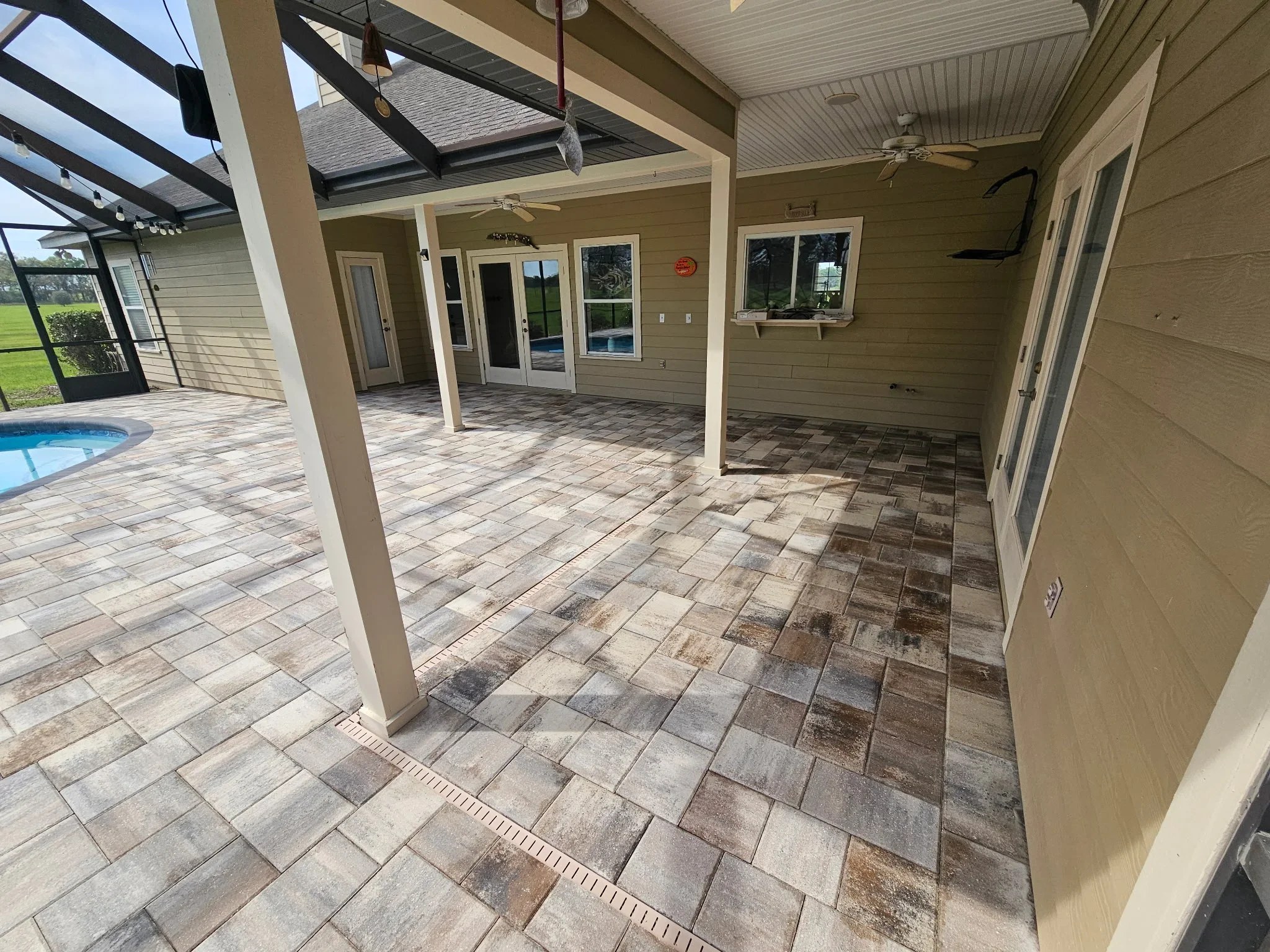 Covered patio with geometric paver design and pool access in Alachua