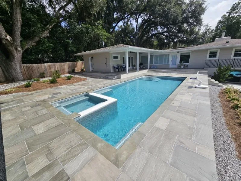 Modern backyard pool with spa, gray pavers, and white covered patio